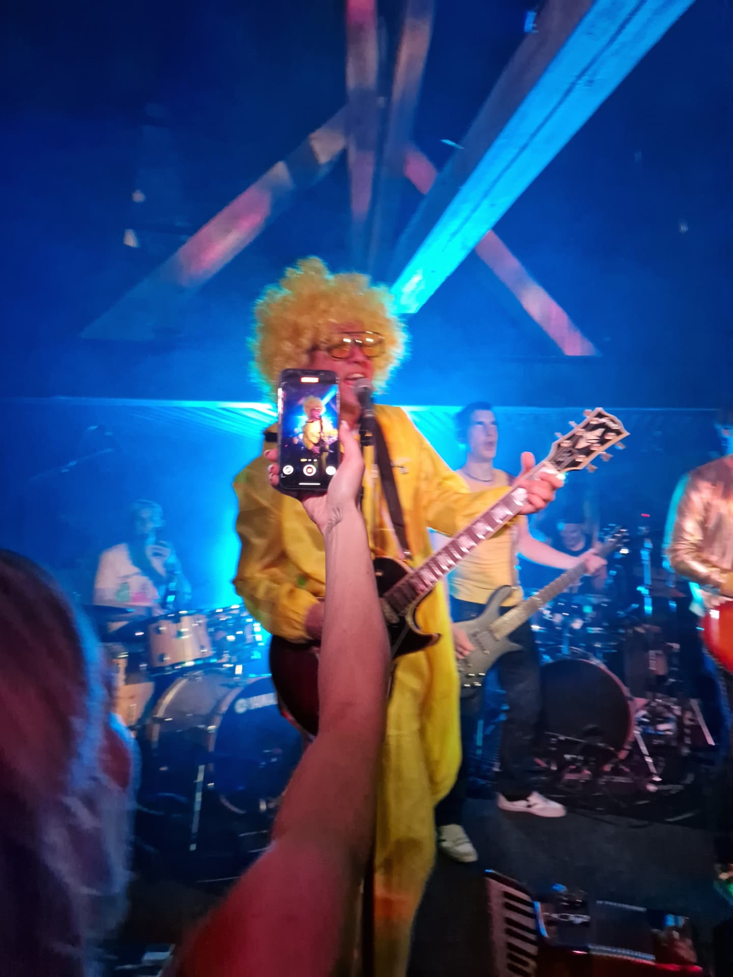 Band member in yellow performing up close with the audience